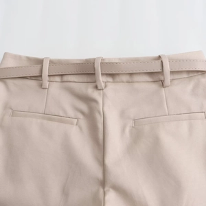 Détail du short beige à taille haute avec ceinture assortie et poches passepoilées