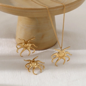 Golden sun-shaped octopus pendant necklace and earrings set on a textured beige fabric
