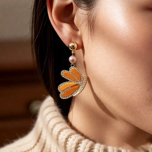 Detail of vintage gold butterfly wing earrings with pearls and orange rhinestones on model