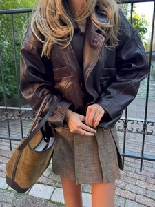 Street style view of oversized brown PU leather jacket paired with a plaid pleated skirt