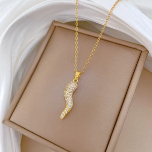 Detailed close-up of a gold chili pepper pendant with sparkling crystal inlay on silk