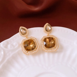 Macro detail of drop-shaped zircon earrings on a classic relief ceramic plate