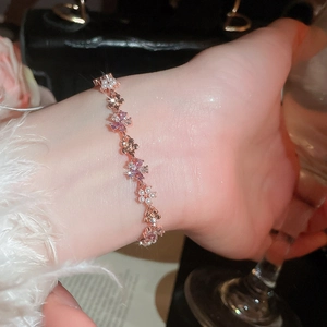 Close-up of rose gold flower bracelet with purple zircons and pearls on wrist