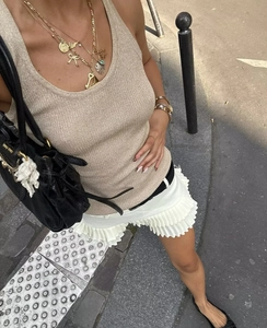 Foto exterior de un top de punto beige con minifalda blanca de capas y volantes