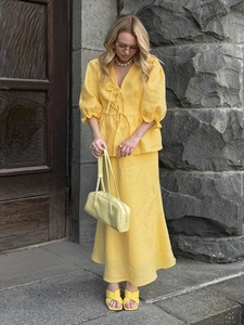 Chic yellow linen set featuring puff sleeve tie-front top and elegant midi skirt