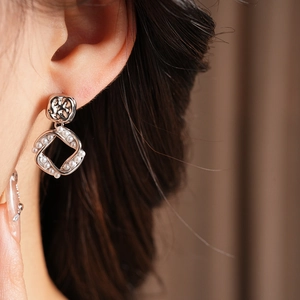 Close-up of square gold-plated frame pearl earring worn on ear for a retro style look