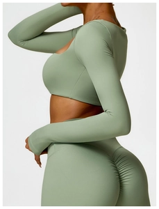 Side view of sage green athletic yoga set featuring long sleeve crop top and ruched leggings
