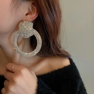 Close-up of model wearing oversized silver hoop earrings with full rhinestone inlay