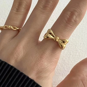 Close-up of a gold bow ring and chain texture ring worn on hand with an elegant minimalist style