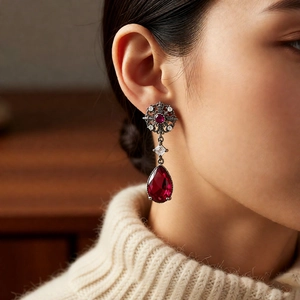 Detail of vintage palace style earrings with red pear-shaped gemstone and zircons