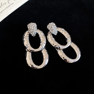 Detail of silver drop earrings with hammered texture and shimmering zircon inlay