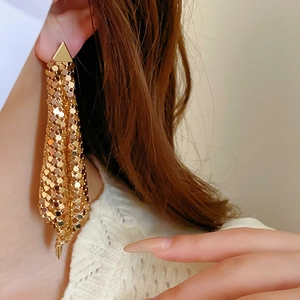 Detailed view of long gold sequin mesh tassel earrings worn for a flowing metallic look
