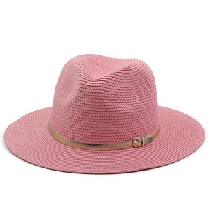 Detail of pink straw sun hat with woven texture and gold leather buckle strap