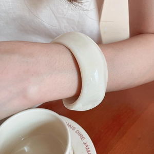 Close-up of cream white resin thick bangle with polished smooth finish on wrist