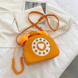 Detail of creative orange patent leather crossbody bag in vintage telephone shape design