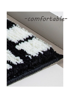 Macro view of thick tufted black and white geometric bathroom mat with soft texture