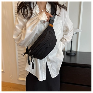 Detail of black canvas chest bag with orange MULAIDI label and woven zipper pulls