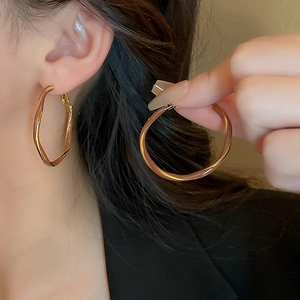 Polished gold wavy hoop earrings for women featuring a stylish twisted geometric design