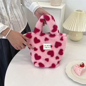 Detail of pink plush handbag with red heart patterns and branded woven label
