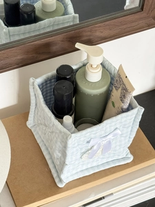 Close-up of light blue quilted fabric storage basket with bow and checkered lining