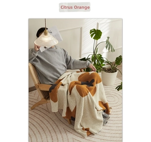 Detail of citrus orange floral knit blanket with cozy plush texture in Nordic home setting