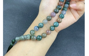Detailed macro view of colorful natural agate beads with a decorative green silk tassel