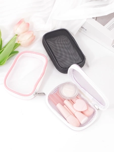 Close-up of translucent mesh makeup bag with metal zipper and cosmetic brushes inside