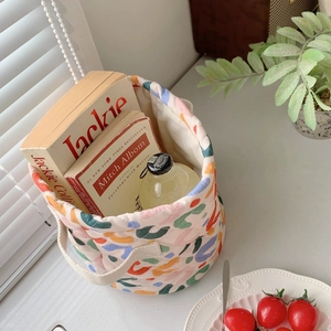 Quilted fabric storage basket with colorful art prints and white woven handles for home organizing