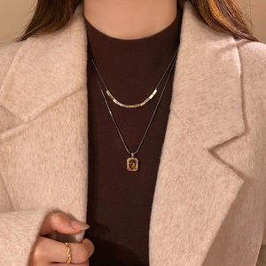 Close-up of layered 18k gold plated necklace with tiger eye stone on model outfit