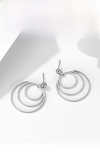 Close-up of geometric triple layered ripple hoop earrings on white marble stone