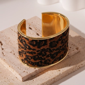 Detail of a leopard print cuff bracelet on elegant beige travertine stone pedestals