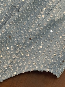 Détail de denim bleu clair avec franges usées et embellissements en paillettes argentées