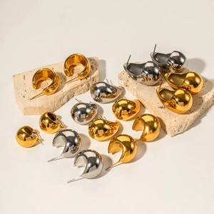 Polished gold and silver hollow teardrop earrings displayed on stone props
