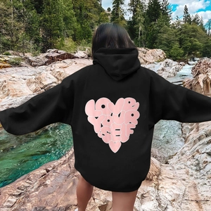 Oversized black hoodie with pink Love Your Self heart print shown in a scenic outdoor setting