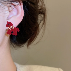 Detail shot of red flocked pony earrings with a gold bow accent on a model ear