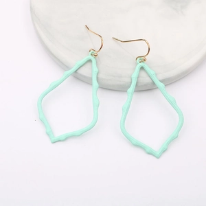 Detailed view of mint green hollow wave earrings on a marble tray background