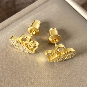 Golden double heart stud earrings with sparkling cubic zirconia on a jewelry display