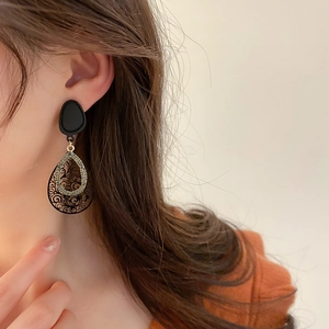 Retro black drop earrings with hollow patterns and rhinestones shown on model side profile