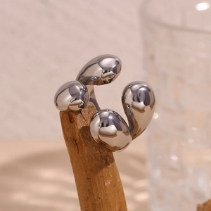 Détail d'une bague ouverte en argent poli avec quatre éléments de galets sur bois