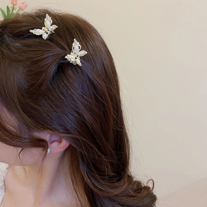 Detail of elegant gold butterfly hair clips with white pearls on model's hair