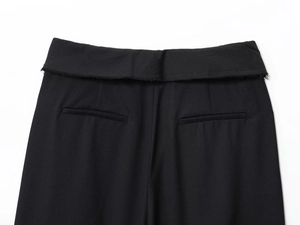 Detail of black pants featuring a unique rolled waistline with raw edges and neat stitching