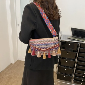 Close-up of bohemian style crossbody bag featuring colorful tassels and woven strap