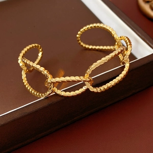 Close-up of gold-plated oval link open cuff bracelet with detailed hammered texture