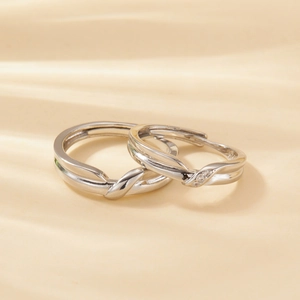 Detail of silver Mobius couple rings with crystals on creamy satin fabric