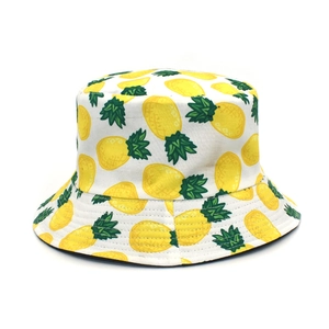 Detail of white cotton bucket hat featuring vibrant yellow and green pineapple prints
