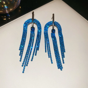 Vue macro de boucles d'oreilles pompon en strass bleus avec tige en argent