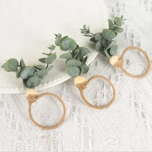 Detail of eucalyptus leaf napkin rings with wooden beads on a white lace tablecloth