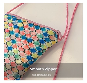 Close-up of pink smooth zipper and shiny mermaid scale texture on children purse