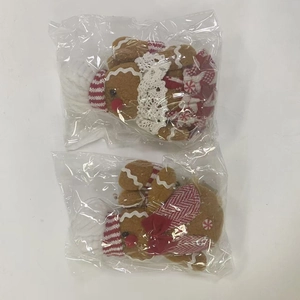 Detail of two gingerbread man plush ornaments in transparent plastic packaging for protection