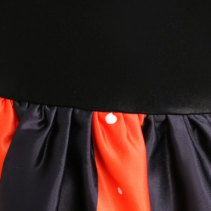 Close-up of Halloween dress featuring glossy orange polka dot satin and pleated black fabric